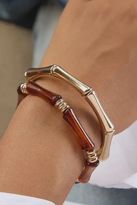 Gold and brown bracelet on a wrist with a blurred background