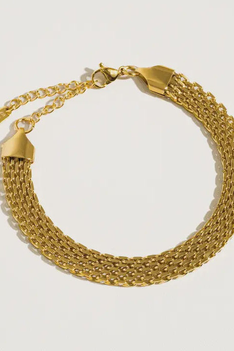 Gold chain bracelet on a light gray background