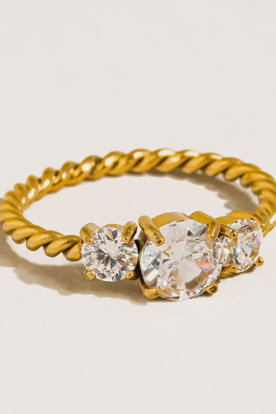 Gold ring with three clear gemstones on a light background