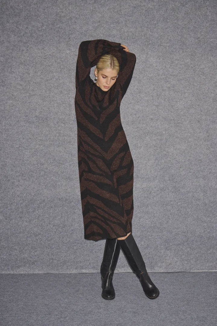 Person wearing a brown and black zebra-striped dress against a gray background