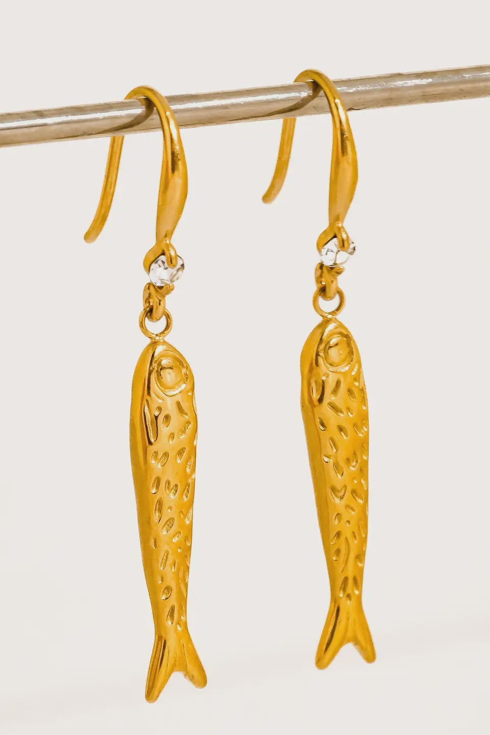 Gold fish-shaped earrings on a white background