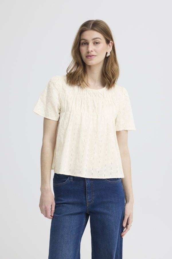 Woman wearing a light-colored t-shirt and blue jeans on a plain background