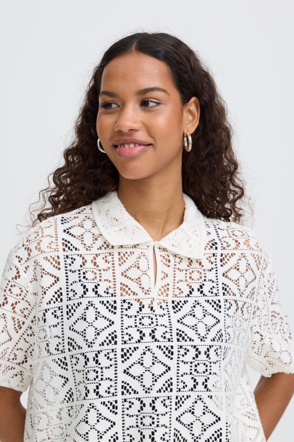 Woman wearing a white lace blouse against a plain background