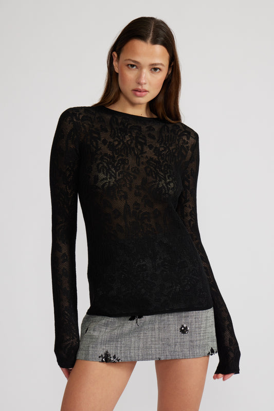 Woman wearing a black lace top and gray skirt on a white background