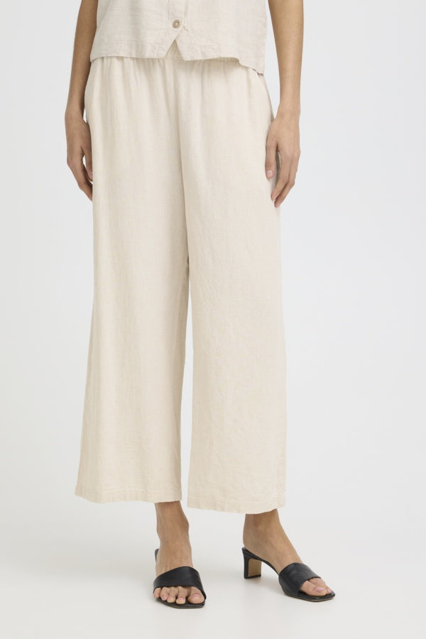 Person wearing beige wide-leg pants and a matching top on a white background