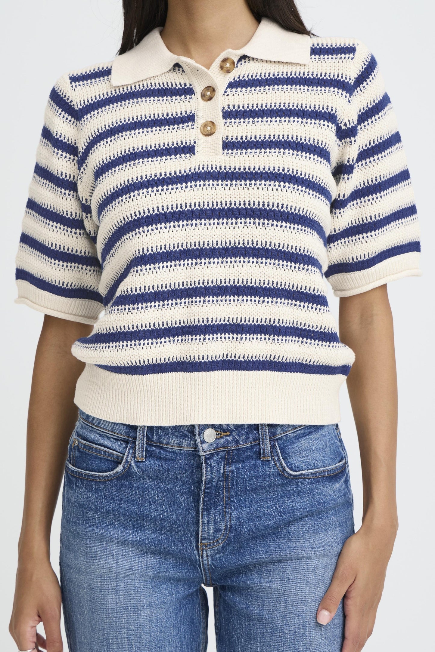 Person wearing a blue and white striped shirt with a collar and blue jeans on a white background