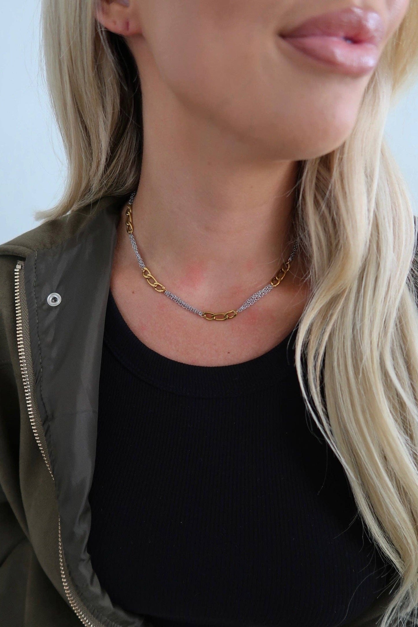 Person wearing a gold necklace with a plain background