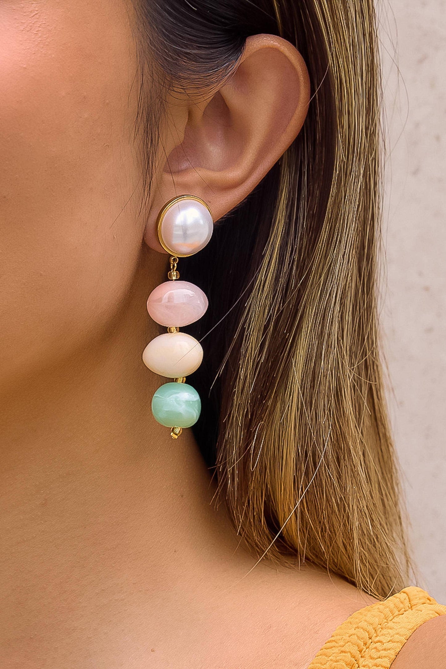 Close-up of an ear wearing a colorful bead earring with a neutral background