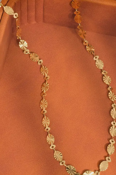 Gold necklace on a rust-colored fabric background