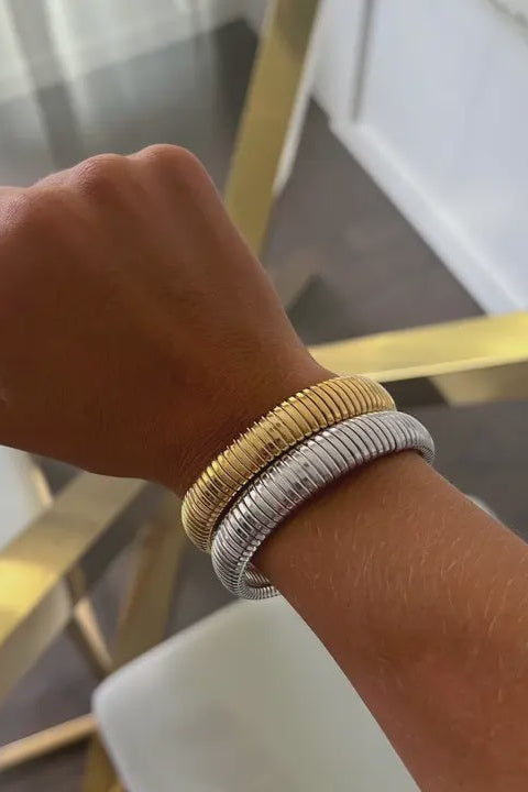 Hand wearing two bracelets on a blurred background