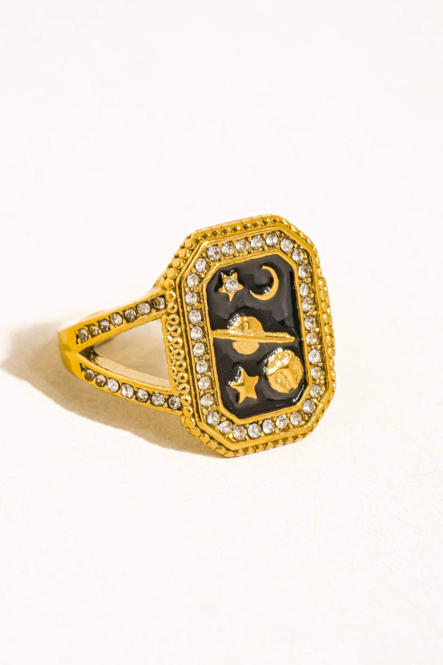 Gold ring with black center featuring celestial design on a white background