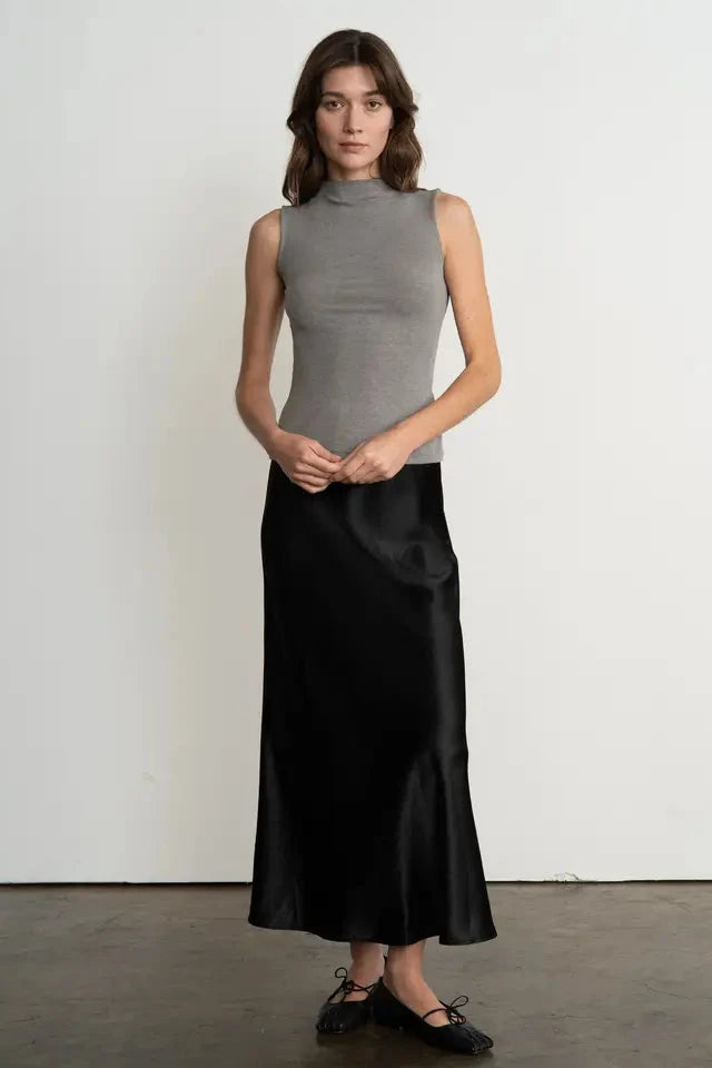 Woman wearing a gray sleeveless top and black skirt against a white background
