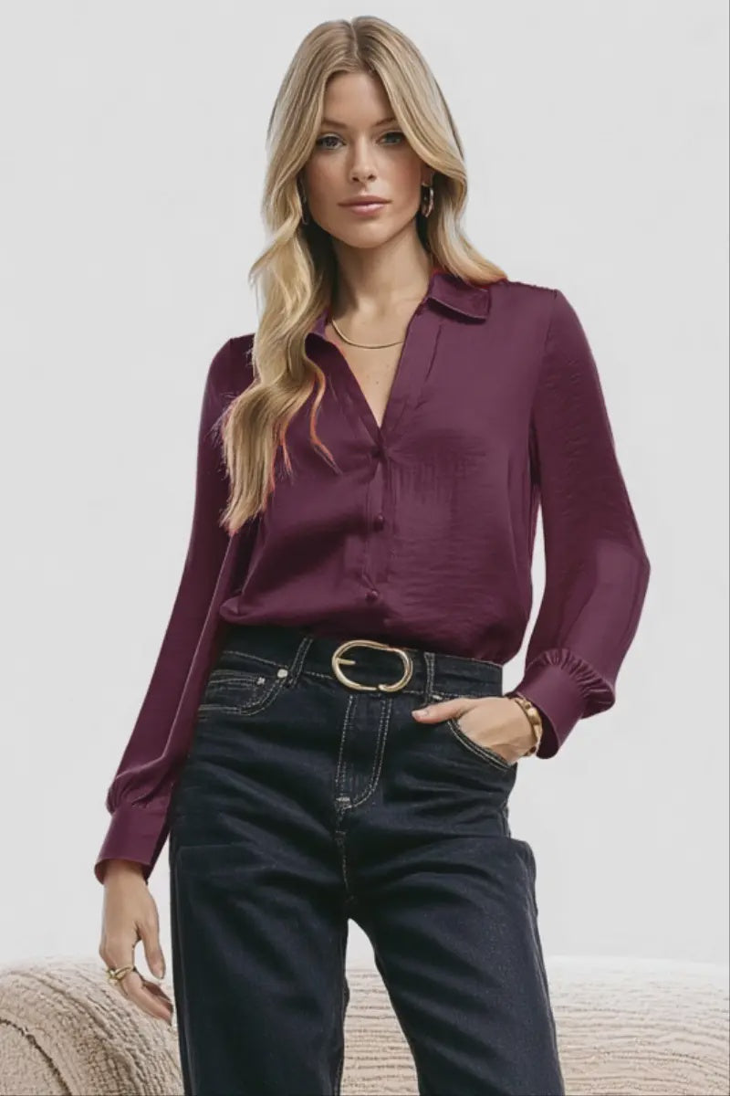 Woman wearing a purple blouse and black pants on a plain background