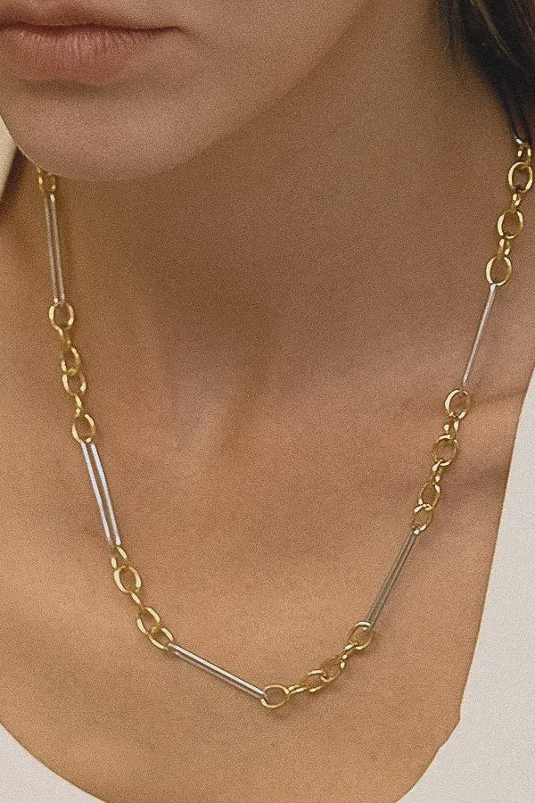 Gold and silver chain necklace worn by a person