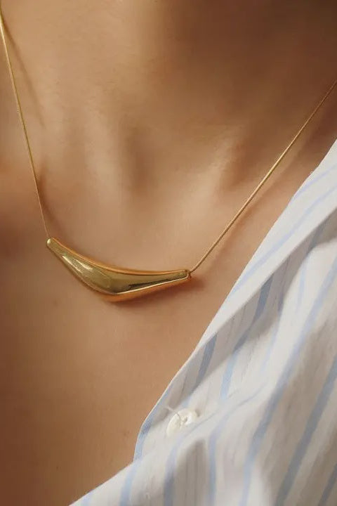 Gold necklace worn by a person with a white shirt with blue stripes.