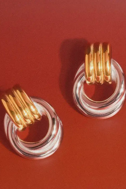 Gold and clear hoop earrings on a red background