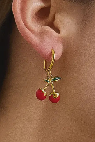 Gold earring with cherry charm worn by a person
