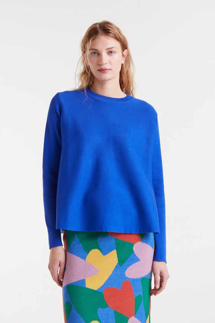 Woman wearing a blue sweater and colorful skirt on a white background