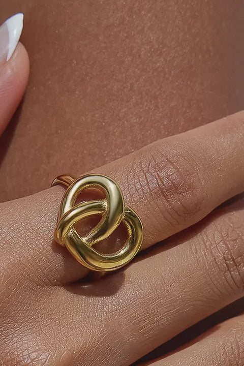 Gold ring with a knot design on a person's finger