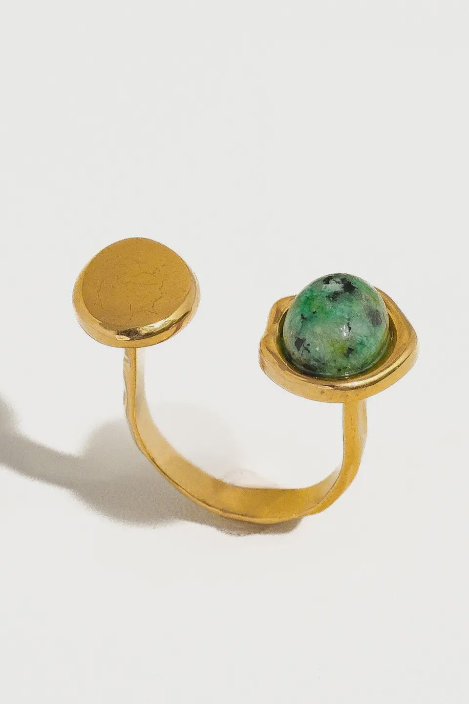 Gold ring with a green gemstone on a white background