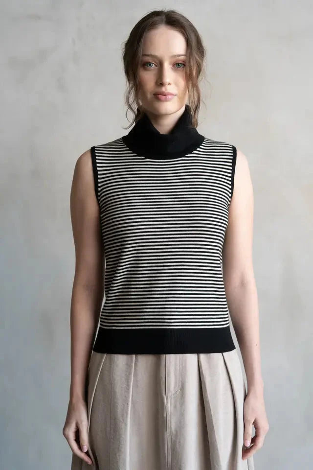 Woman wearing a black and white striped sleeveless top with a plain background