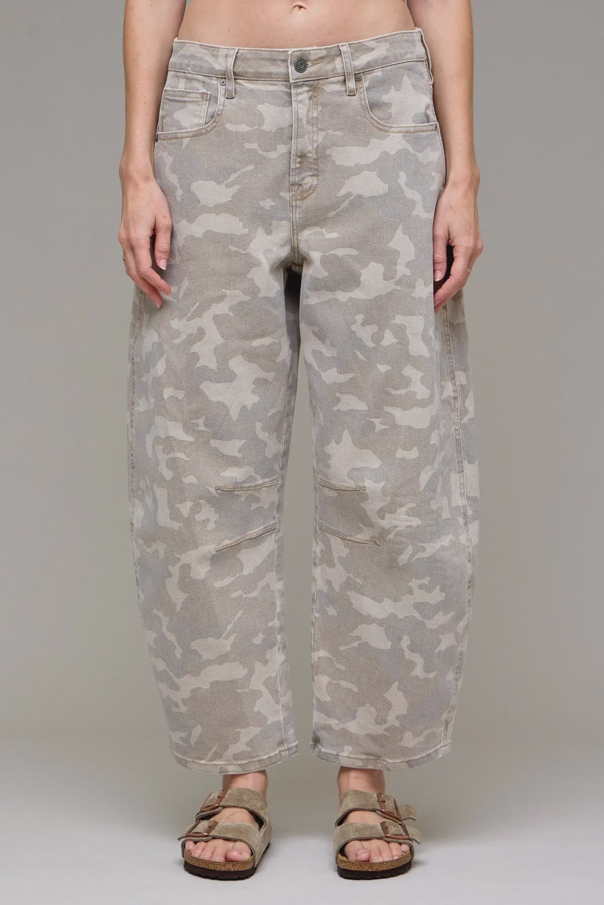 Camouflage pants worn by a person on a plain background