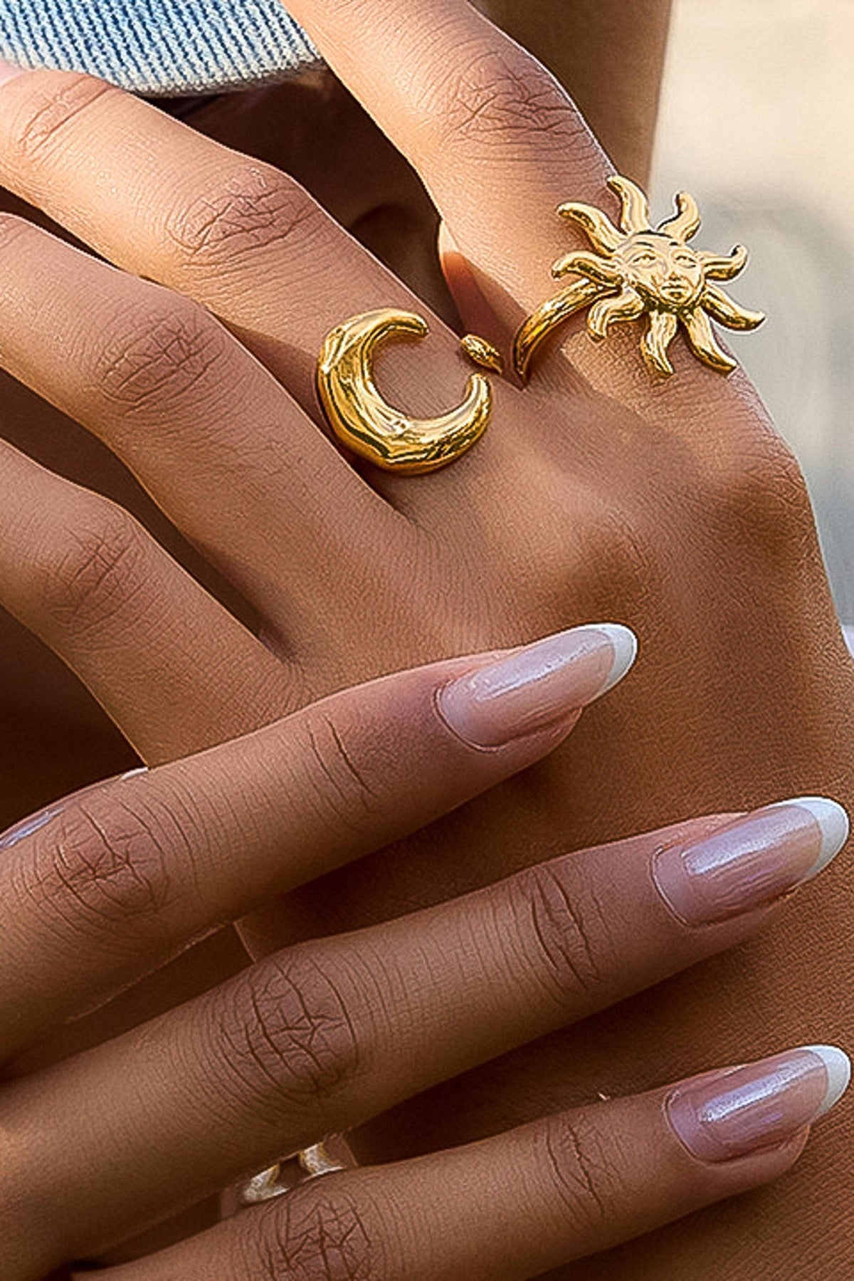 Gold sun and moon ring on a hand with blurred background
