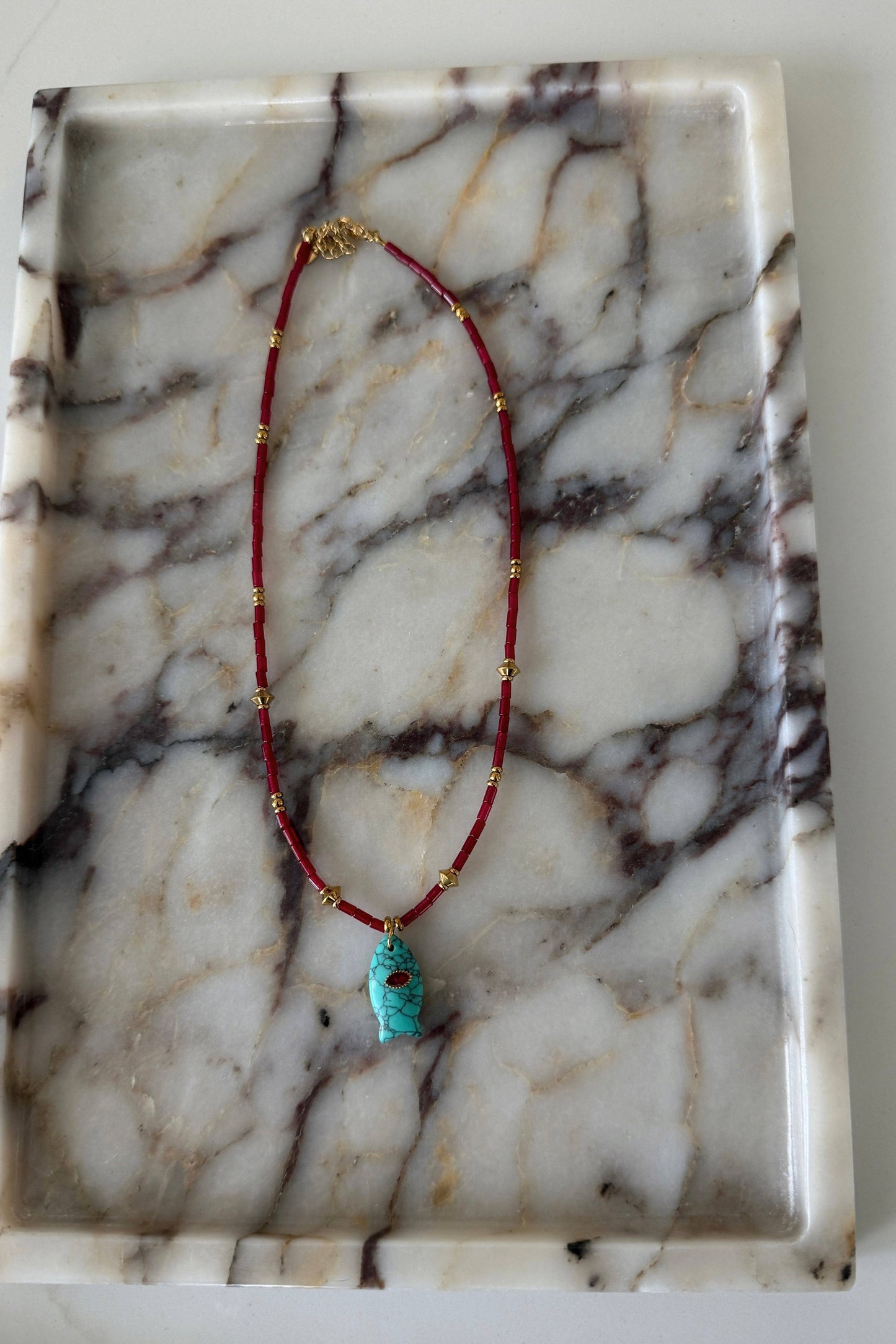 Necklace with a turquoise pendant on a marble surface