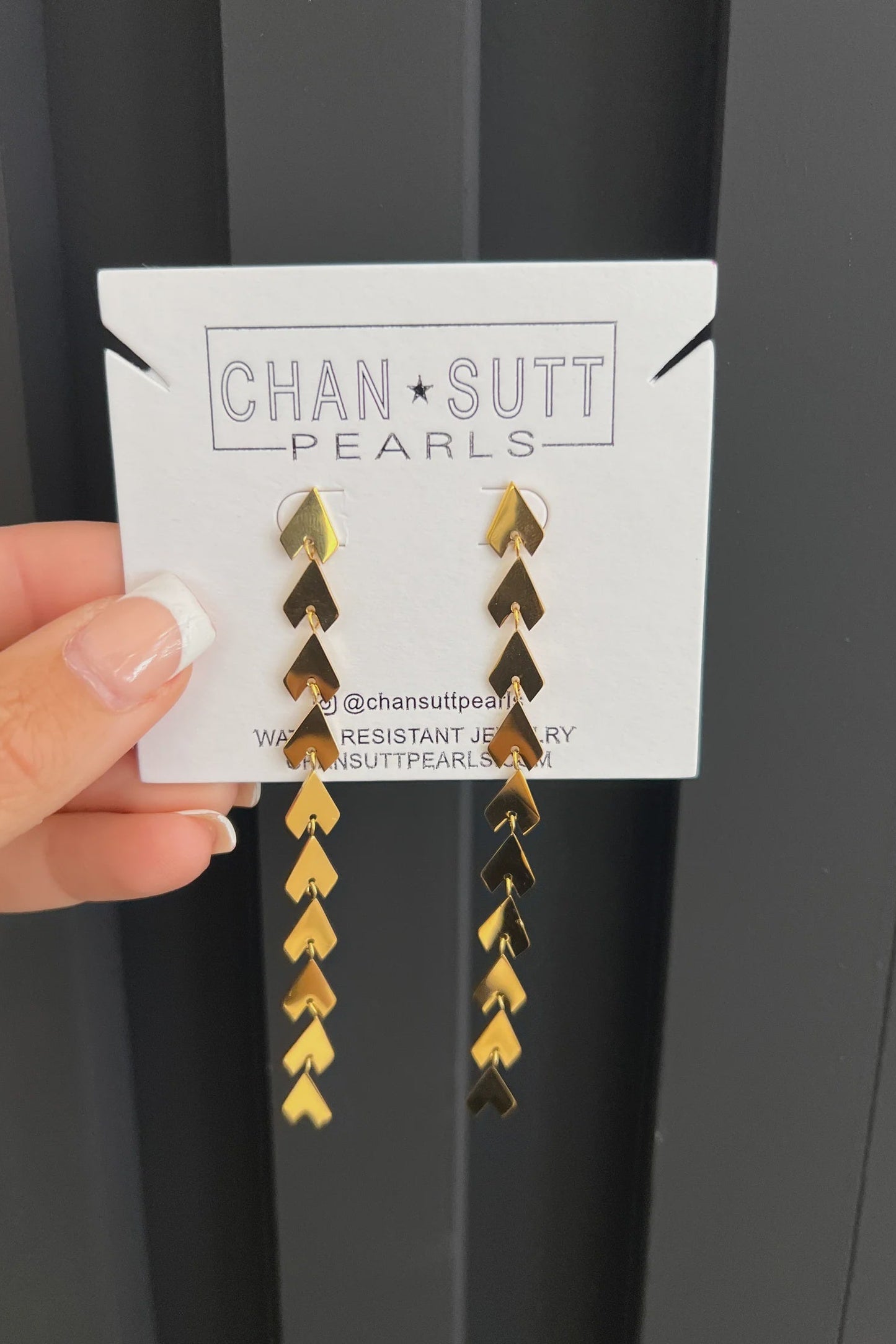 Gold and black chevron patterned earrings on a Chansutt Pearls card against a black background