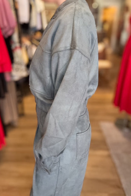 Gray jumpsuit worn by a person in a clothing store with blurred background