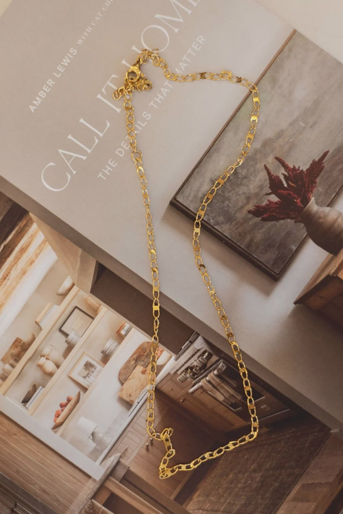 Gold necklace on a book titled 'Call It Home' by Albert Lewis and Sarah Walker.