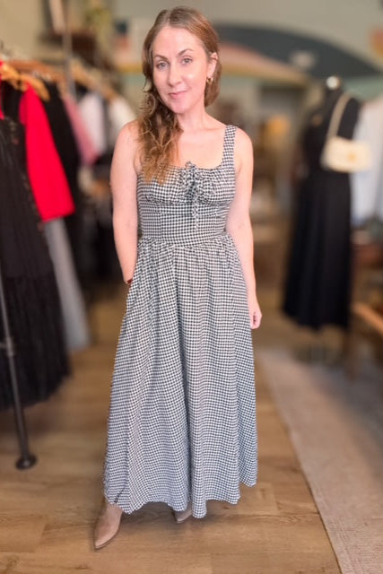 Woman wearing a black and white checkered dress in a clothing store.