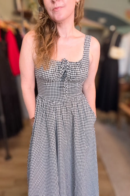 Woman wearing a black and white checkered dress in a clothing store.