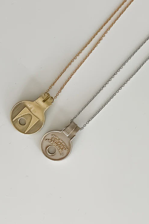 Two round pendant necklaces on fine chains, one in gold and one in silver, displayed on a clean white background.
