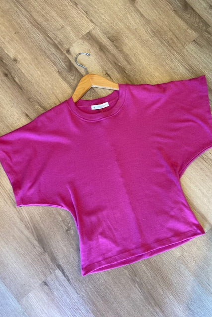 Pink t-shirt on a wooden hanger on a wooden floor