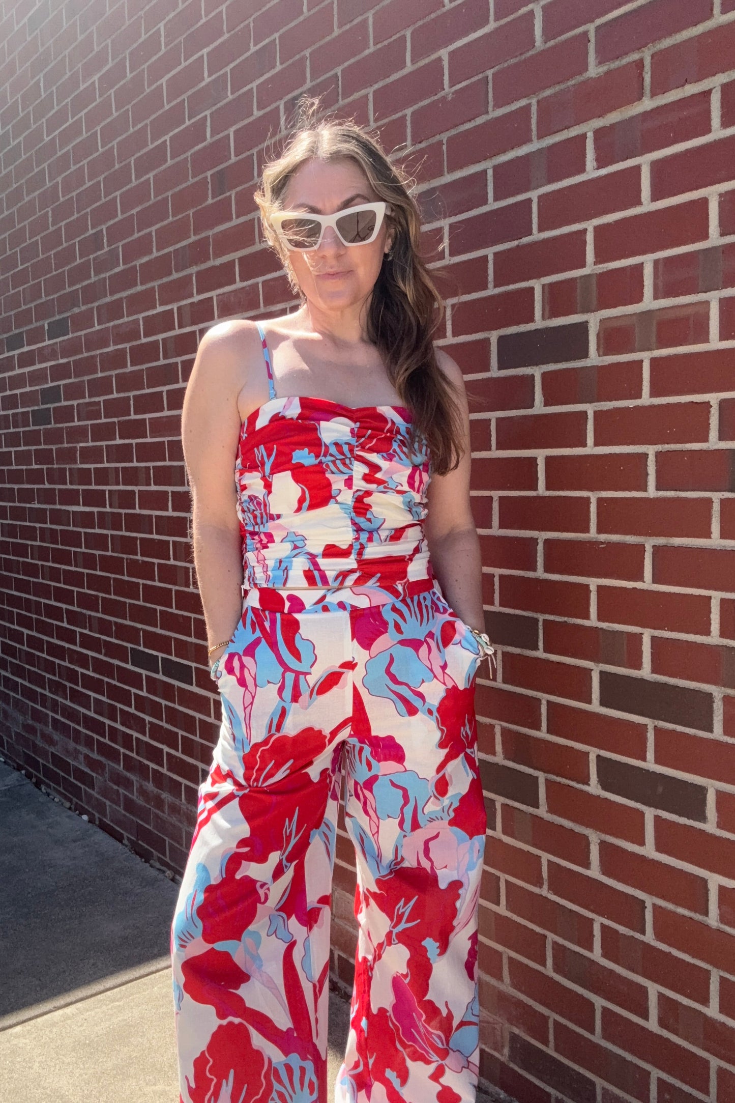 Person wearing a red and white floral dress on a brick pavement