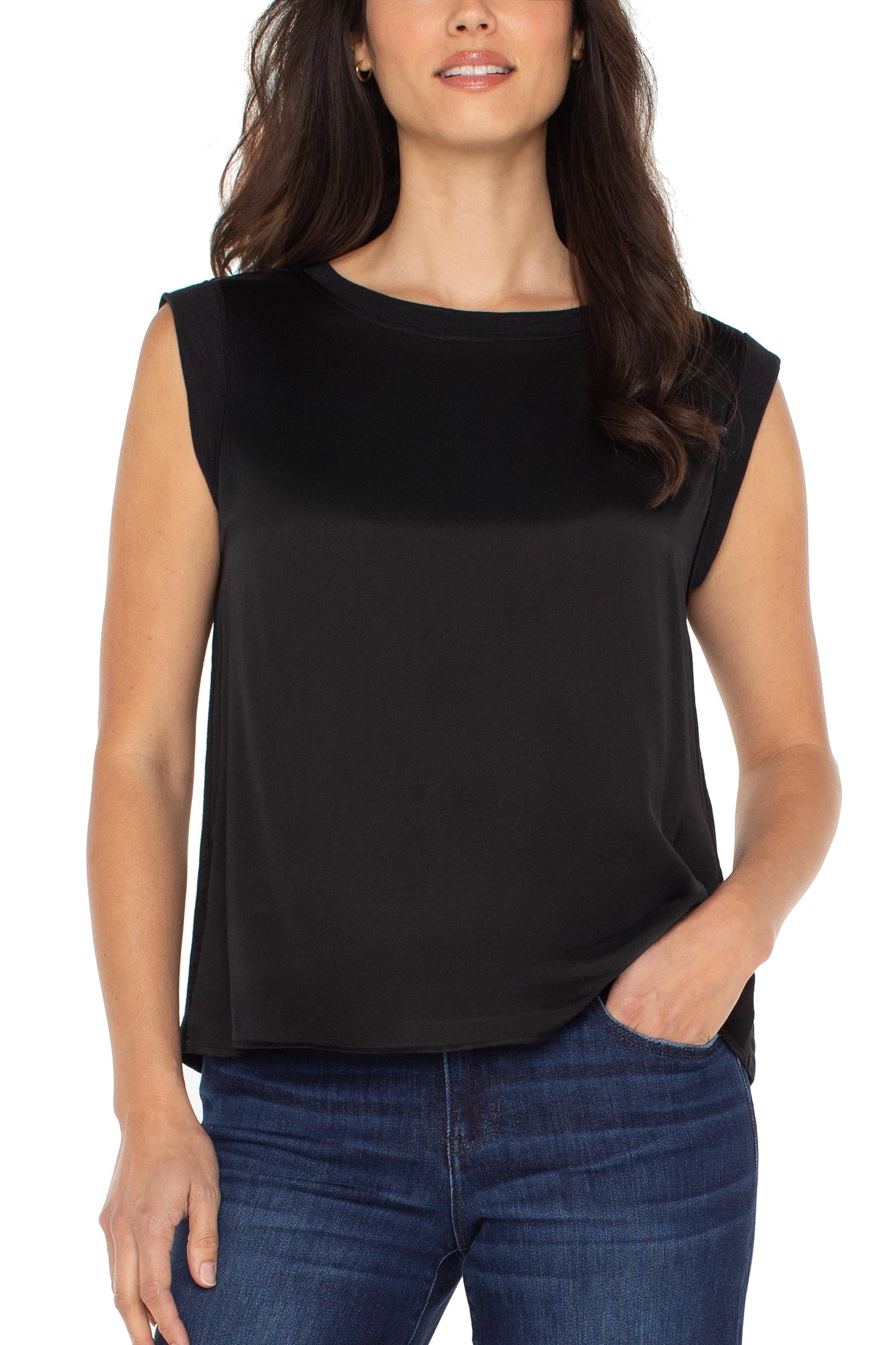Woman wearing a black sleeveless top and blue jeans on a white background