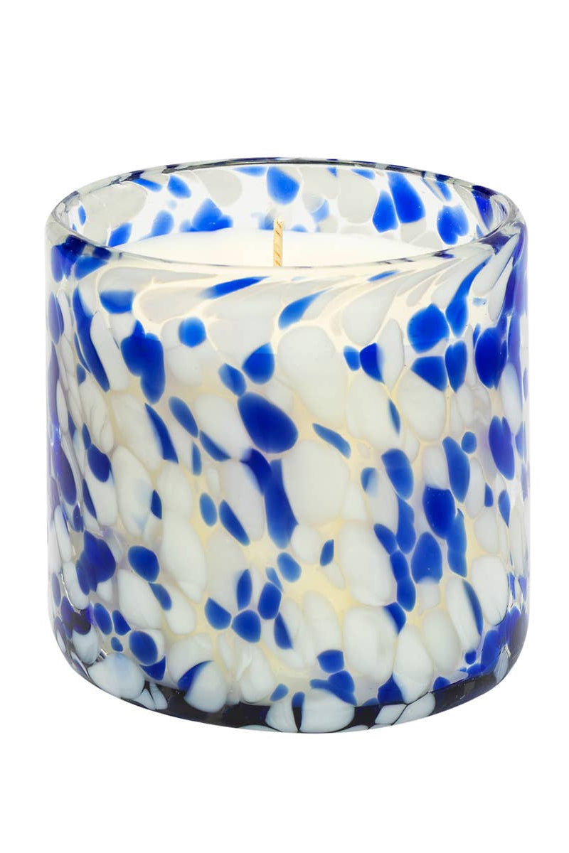Candle in a blue and white speckled glass container on a white background