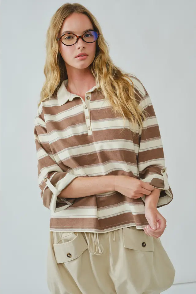 Woman wearing a brown and beige striped shirt with a plain background