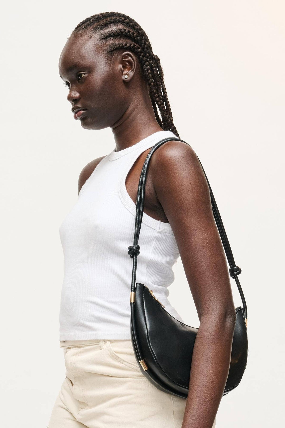 Woman carrying a black handbag on a plain background
