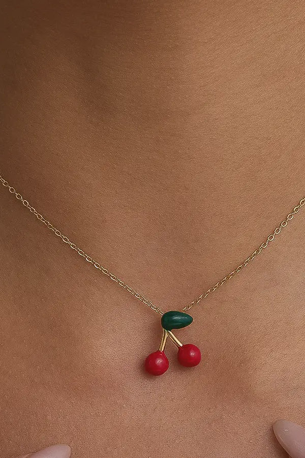 Necklace with cherry pendant on a person's neck against a neutral background