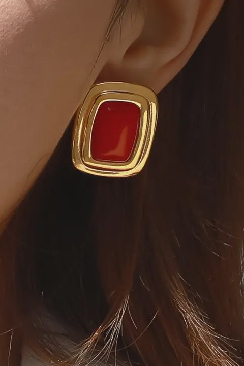 Gold earring with a red stone on an ear