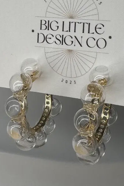 Gold and clear hoop earrings on a card with 'Big Little Design Co' branding.