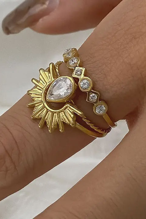 Gold ring with a central gemstone on a finger against a neutral background