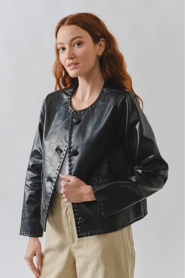 Woman wearing a black leather jacket against a plain background
