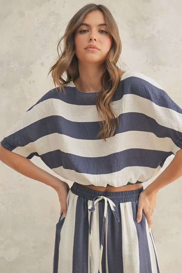 Woman wearing a navy and white striped outfit against a neutral background