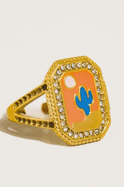 Gold ring with a blue cactus design on an orange background