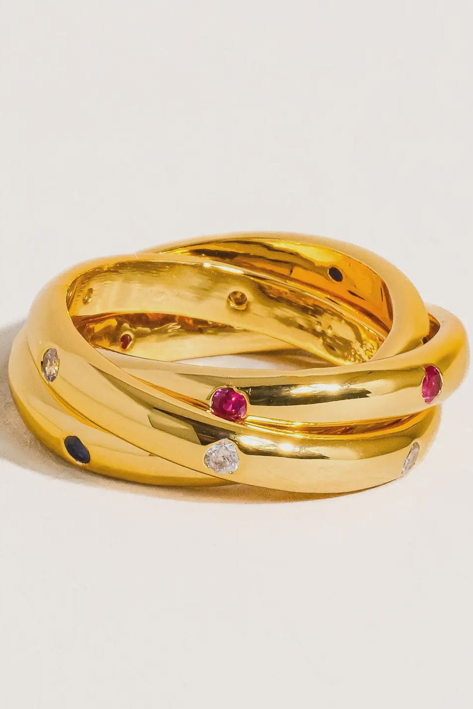 Gold ring with embedded gemstones on a light beige background