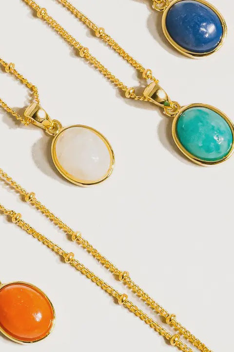 A series of round necklaces with gold-colored settings and multicolored gemstone pendants.