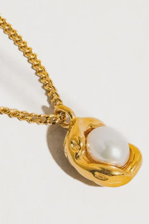 A gold-colored necklace with a white pearl-shaped pendant.